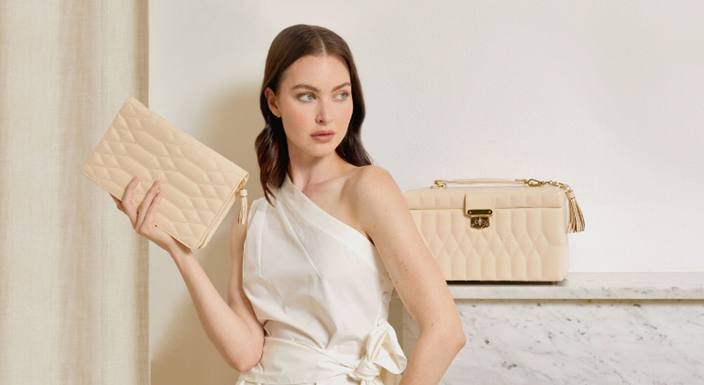A woman holding a WOLF jewellery portfolio with a jewellery box behind her. 
